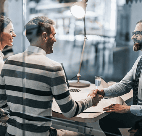 Two people shaking hands across a desk during a lending consultation
